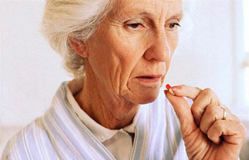 пожилая женщина пьет таблетку
